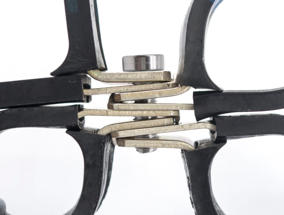 close-up of multiple coins squeezed tightly between the handles of two universal clamps against a white background.