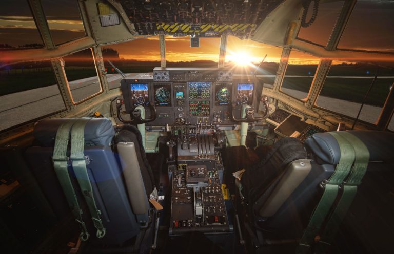 cockpit view at sunset with sun peering through the windshield, showcasing detailed flight instruments and two pilot seats in a lockeed martin aircraft.