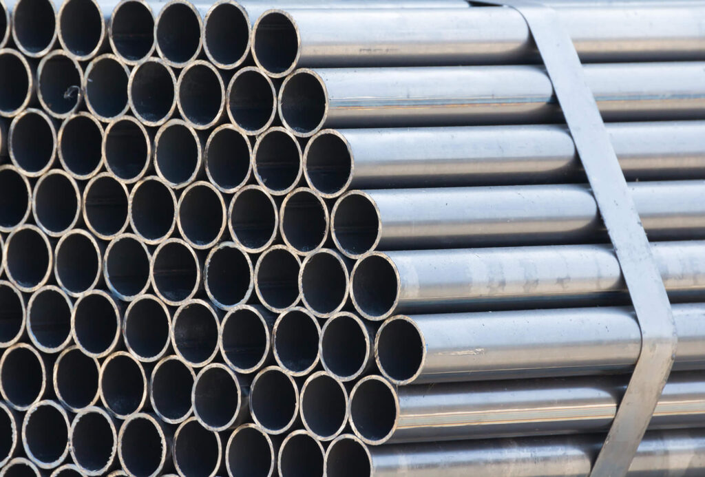 Stack of metal pipes with circular cross-sections, aligned horizontally on a rack.